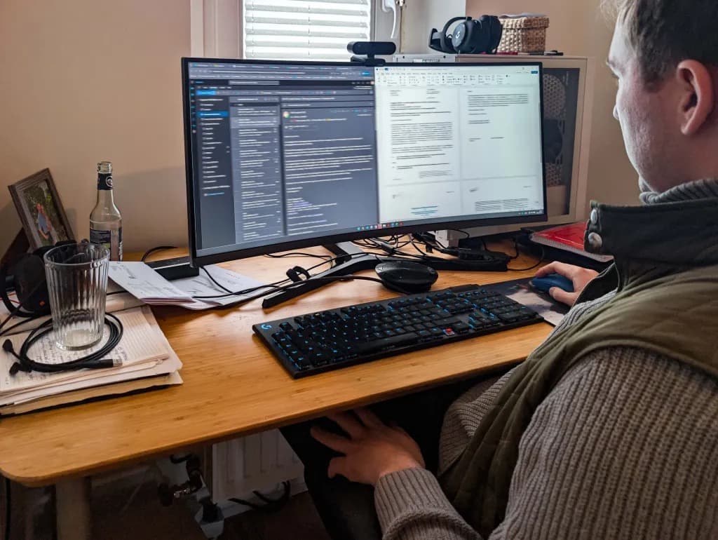 A man working at a dual monitor desk setup at home
