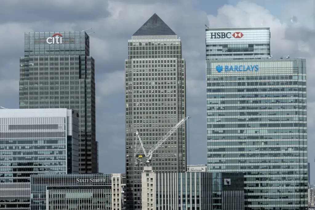 Skyscrapers in London's Canary Wharf financial district displaying bank logos including Citi, HSBC, and Barclays