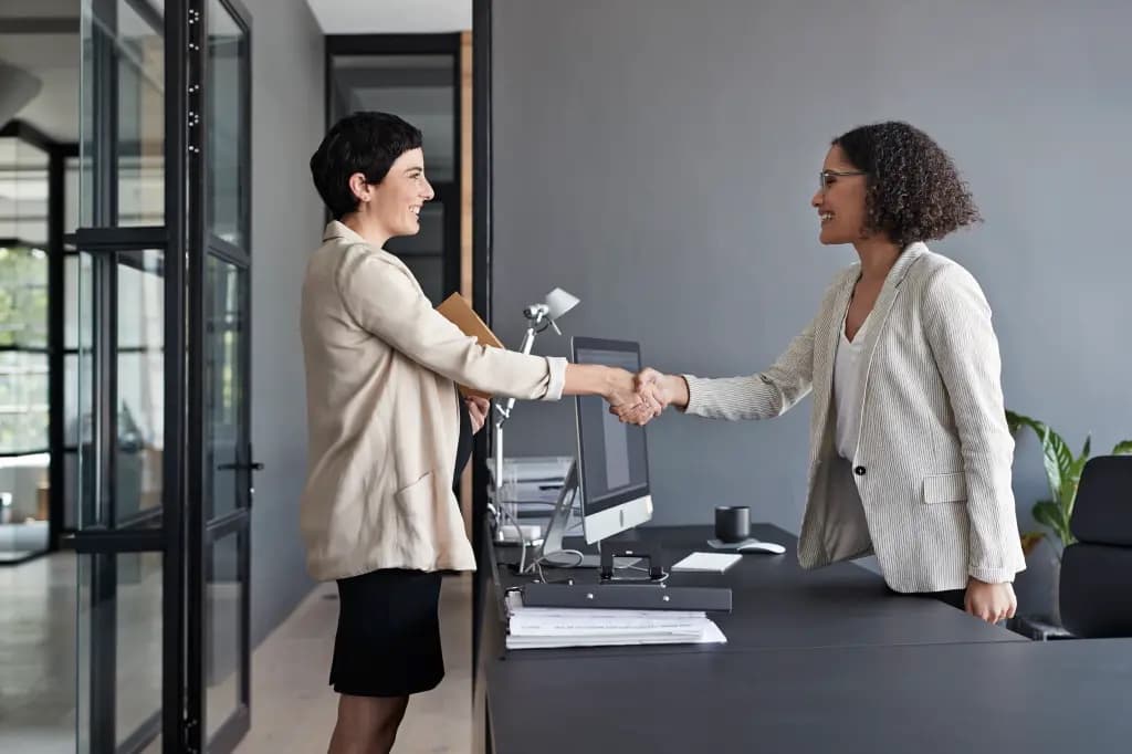Two businesswomen shaking hands in an office