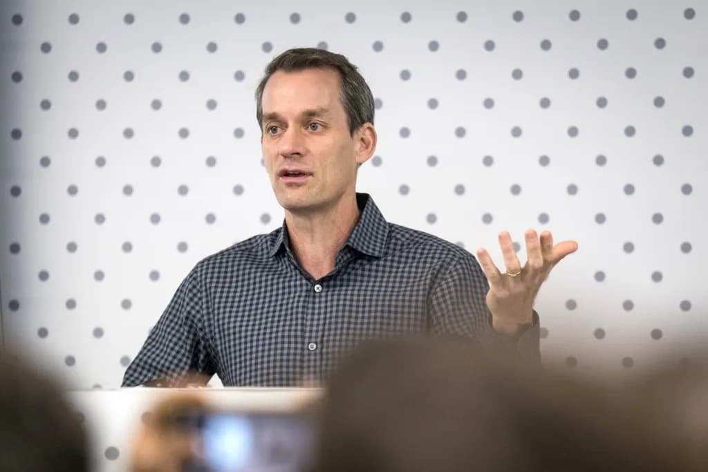 Jeff Dean gesturing while speaking at an event in front of a patterned backdrop