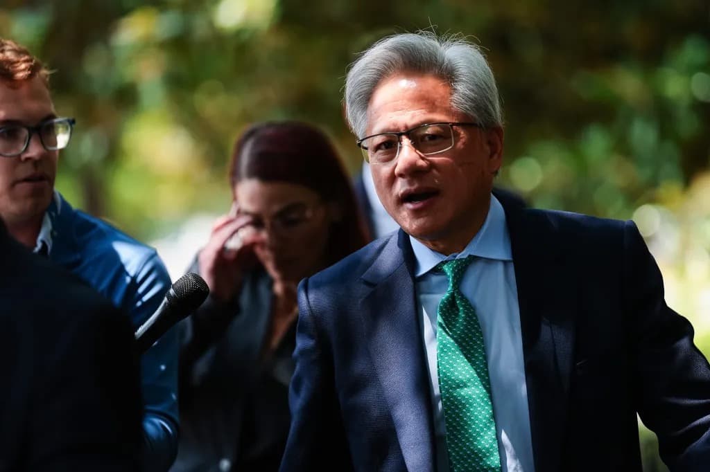 Jensen Huang speaking into a microphone while walking outdoors, flanked by two other people