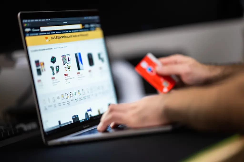 A person holding a credit card while shopping online on a laptop