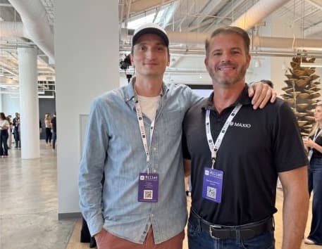 Branden Jenkins standing with another man at a conference, both wearing event lanyards