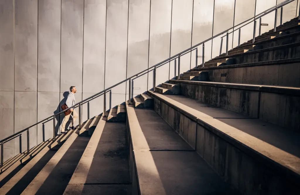 A businessman climbing a large outdoor staircase