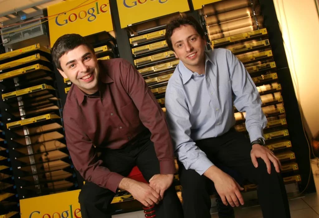 Larry Page and Sergey Brin sitting together in a Google server room