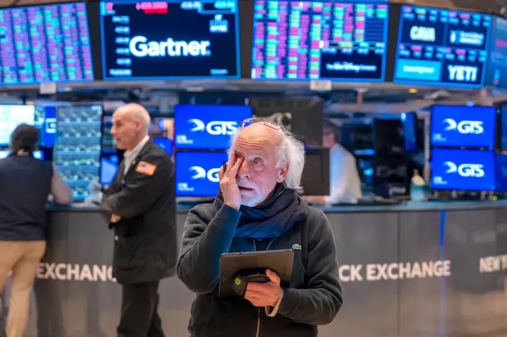 A trader on the floor of the New York Stock Exchange looking up at screens