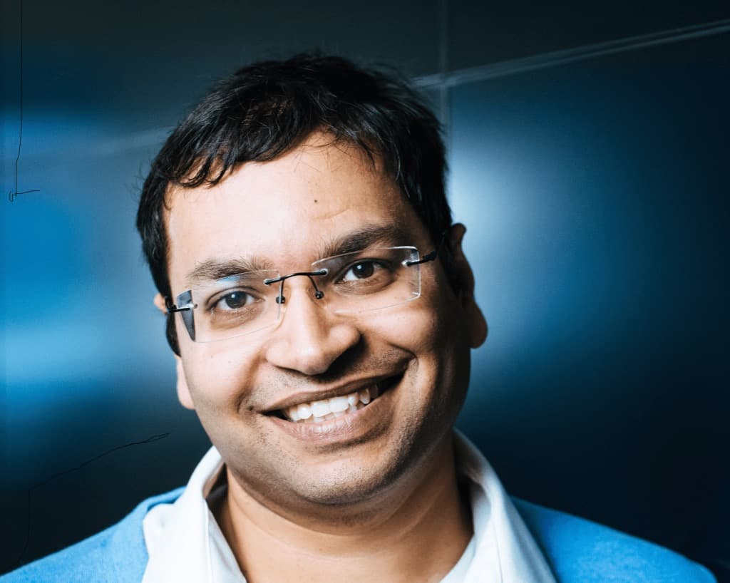 Portrait of author Rakesh Kumar smiling against a dark blue background